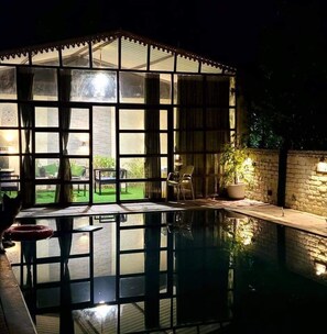 Ein Poolbereich mit Glasveranda, einem Stuhl und einem Blumentopf.