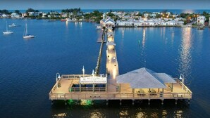 Un moll s'estén sobre una calma massa d'aigua, amb un cartell que diu "Welcome Bradenton Beach Pier".