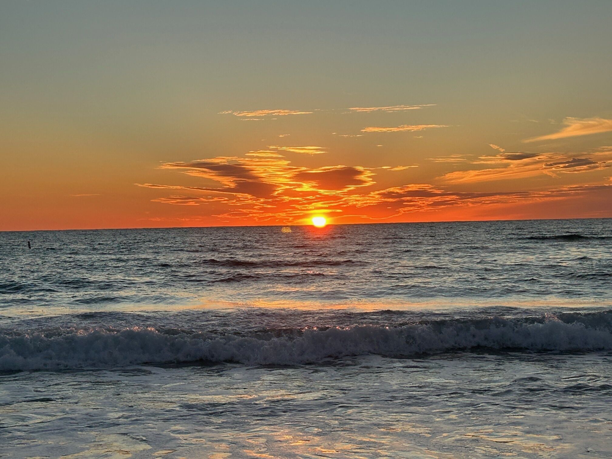 A sunset over the ocean with waves.