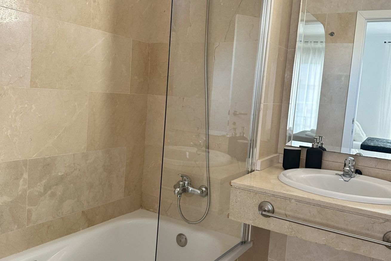 Un baño moderno con ducha envuelta en vidrio, una bañera y un lavamanos con lavabo y espejo.