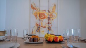 Une table à manger avec des assiettes, des verres et un plat de fruits contenant des bananes et des pêches.