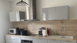 A modern kitchen with a microwave, toaster, oven, and sink. - Bel et Spacieux Appartement (Rives)
