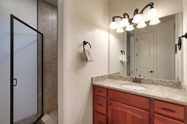 Une salle de bain avec une douche, un lavabo avec un meuble-vasque et un miroir avec éclairage.