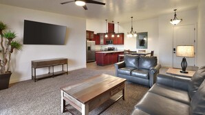 A modern living room with a sofa, coffee table, and a TV mounted on the wall.