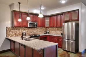 A kitchen with a central island, stainless steel appliances, and a stone backsplash.