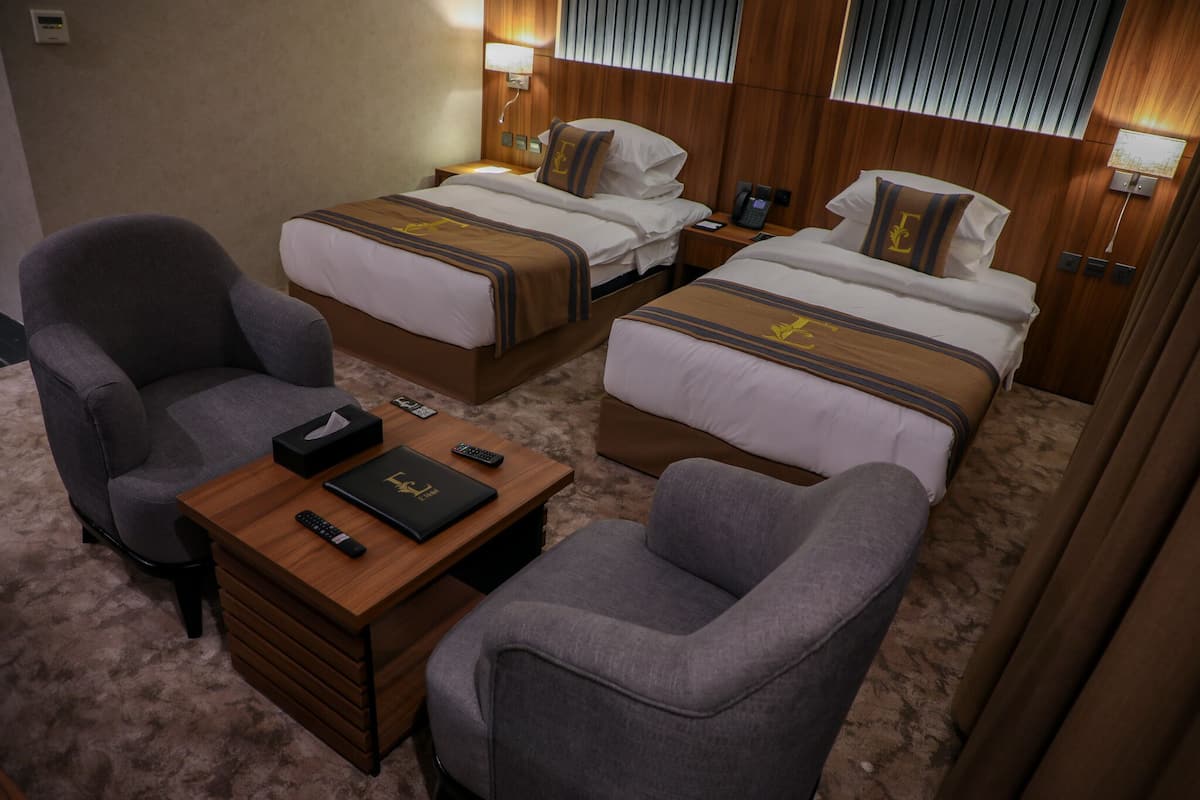 Une chambre d’hôtel avec deux lits, un bureau et deux fauteuils.
