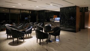 A modern lobby with black upholstered chairs, a reception desk, and a marble floor. - E hotel (Madinah)