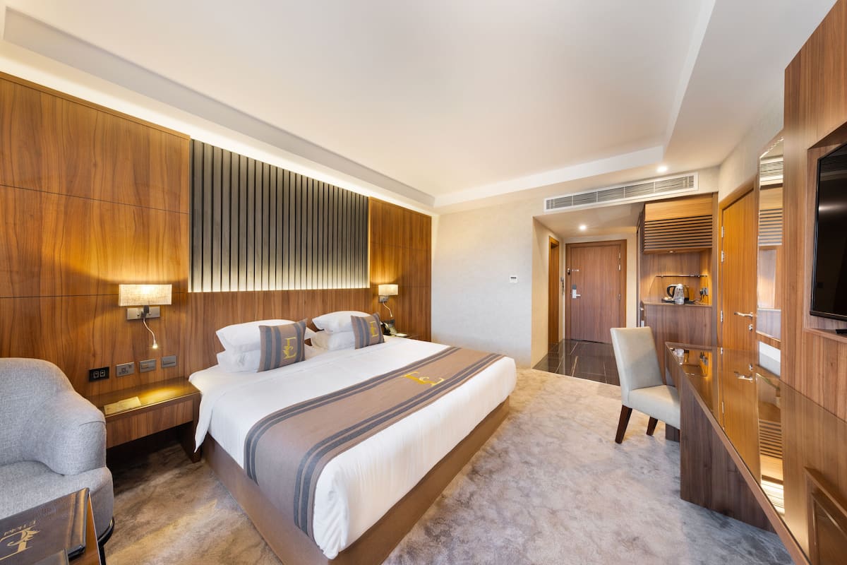 Une chambre d’hôtel moderne avec un grand lit, un bureau et une télévision.