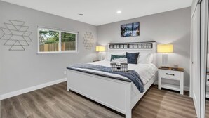 A modern bedroom with a bed, bedside tables, and a window.