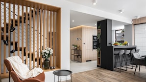A modern kitchen with wooden cabinets, a black countertop, and a bar area with stools.