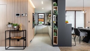 A modern kitchen with built-in appliances, a dining area with a black chair, and a vertical garden unit.