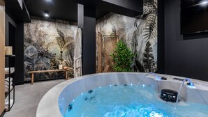A modern bathroom with a hot tub, a shower area, and a wall with a leaf pattern.