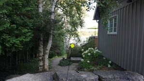 A garden with a yellow sign, a wooden deck, and a shed. - Starlight Shores - Serene Lakefront Retreat: Explore and Unwind (Miller Lake)