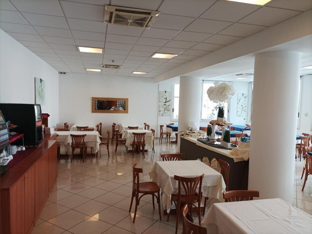 A restaurant with multiple tables and chairs, a counter with a display, and a large window with a view.