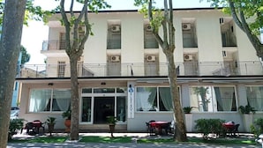 A two-story hotel with a balcony on the upper floor, large windows, and outdoor seating area.