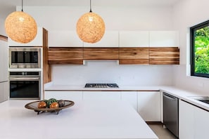 A modern kitchen with white cabinetry, a central island, a built-in oven, and a stove.