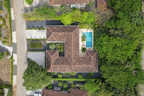 An aerial view of a property with a swimming pool, multiple buildings, and surrounding greenery.