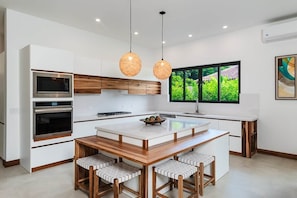 A modern kitchen with white cabinetry, a central island, and pendant lighting.