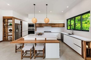 A modern kitchen with a central island, wooden cabinetry, and pendant lighting.