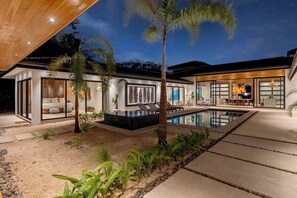 Una casa moderna con piscina, area relax all'aperto e un cielo stellato.