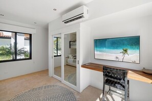 Una camera moderna con una grande finestra, un quadro raffigurante una spiaggia, una scrivania in legno e una sedia.
