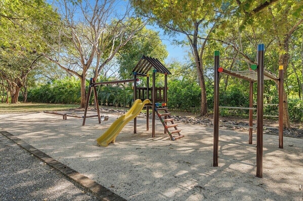 A playground with a slide, climbing structures, and a small shelter.