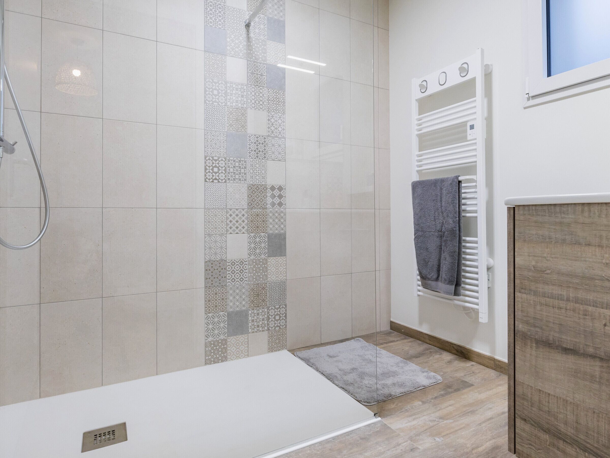 Une salle de bain moderne avec une douche, un porte-serviettes et un plancher en bois.