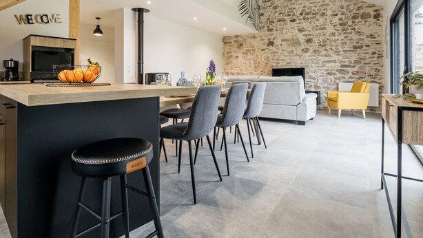 Eine moderne Küche mit Steinwand, einer Holztreppe und einer Bar mit Hockern.