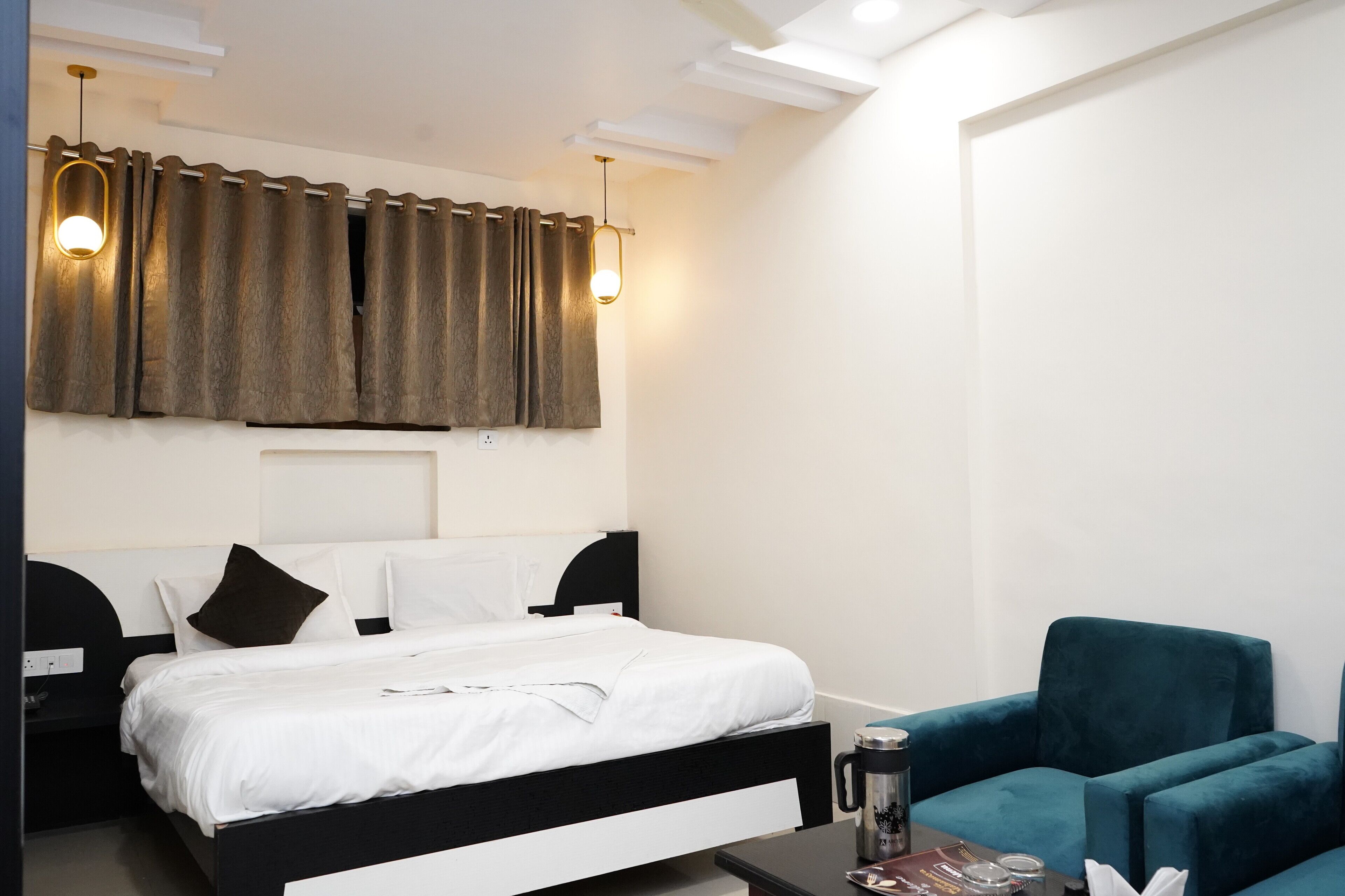 Una habitación de hotel moderna con una cama bien hecha, una mesita con una taza, y un sillón color turquesa.