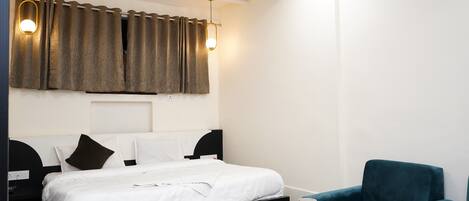 Una habitación de hotel moderna con una cama bien hecha, una mesita con una taza, y un sillón color turquesa.
