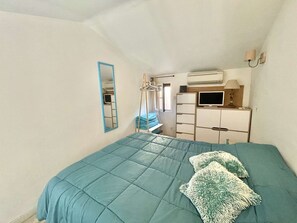 A bedroom with a bed, a mirror, a dresser, a TV, and a window.