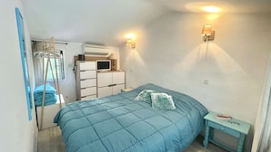 A bedroom with a bed, a dresser, a mirror, and a wall-mounted heater.