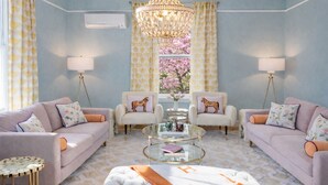 A living room with two sofas, a glass coffee table, and a chandelier.