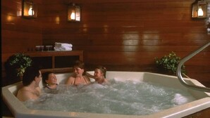 A hot tub with three people, wooden walls, and wall-mounted lights. - Deluxe Mountain Fox Suite Jiminy Peak - Ski On Off - Fully Redone Decor (Hancock)