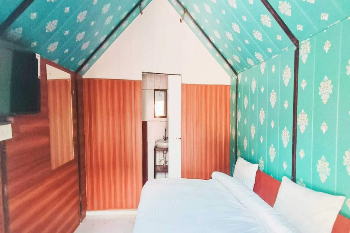 A bedroom with a bed, a mirror, and a bathroom visible through an open door.