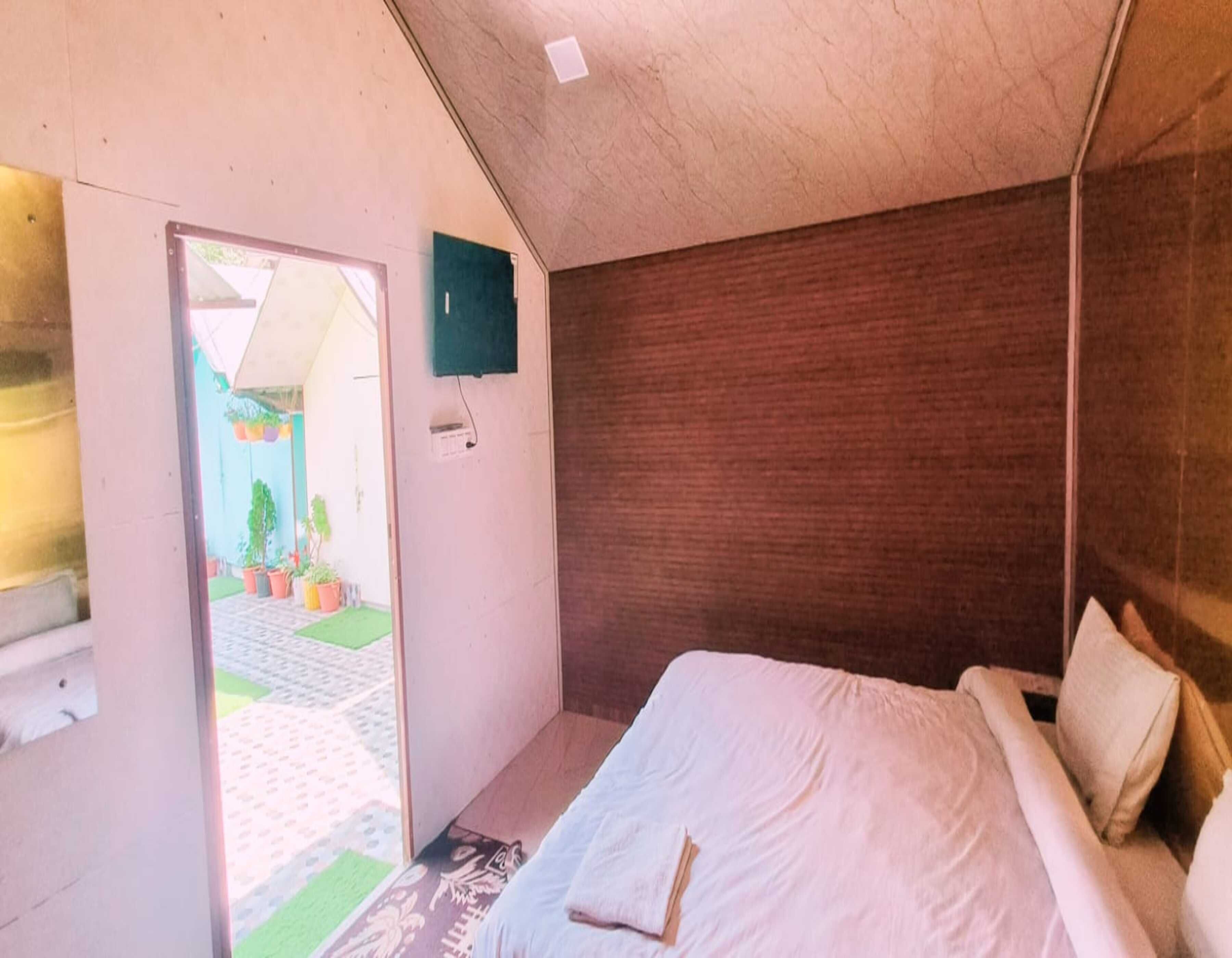 Une chambre à coucher avec un lit, une porte donnant sur l’extérieur et un petit luminaire fixé au mur.