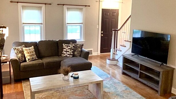 A living room with a sofa, coffee table, and a TV. - The House Hotels - Superior Road (Cleveland Heights)