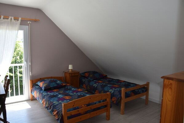Un dormitorio con dos camas de madera, una mesita de noche y una ventana con cortina.