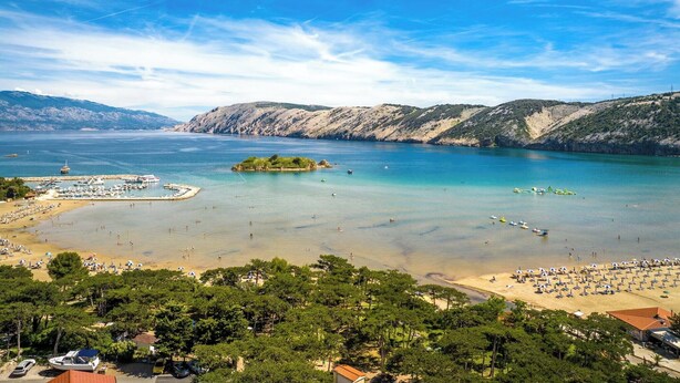 Eine Küstenlandschaft mit Strand, Booten und einem Yachthafen.
