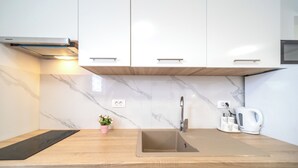 Eine moderne Küche mit weißen Schränken, einer Marmor-Spritzschutzwand, einer Edelstahl-Spüle und einer Holzarbeitsplatte.