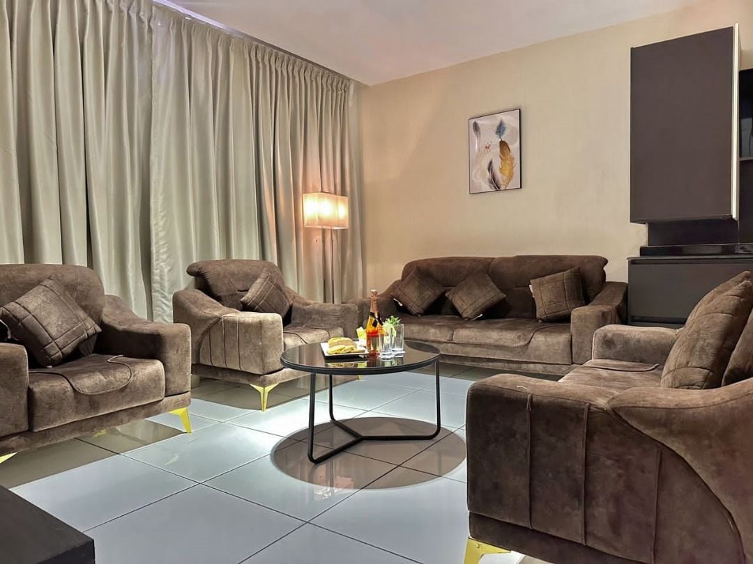 Een woonkamer met een bank, een salontafel, een flatscreen televisie en een lamp.