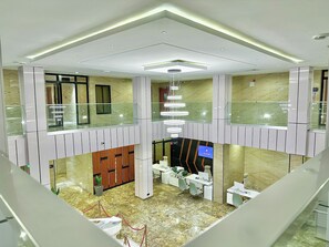 A modern hotel lobby with a glass balustrade, a chandelier, and a reception desk. - Boulevard Owerri Hotel (Owerri)