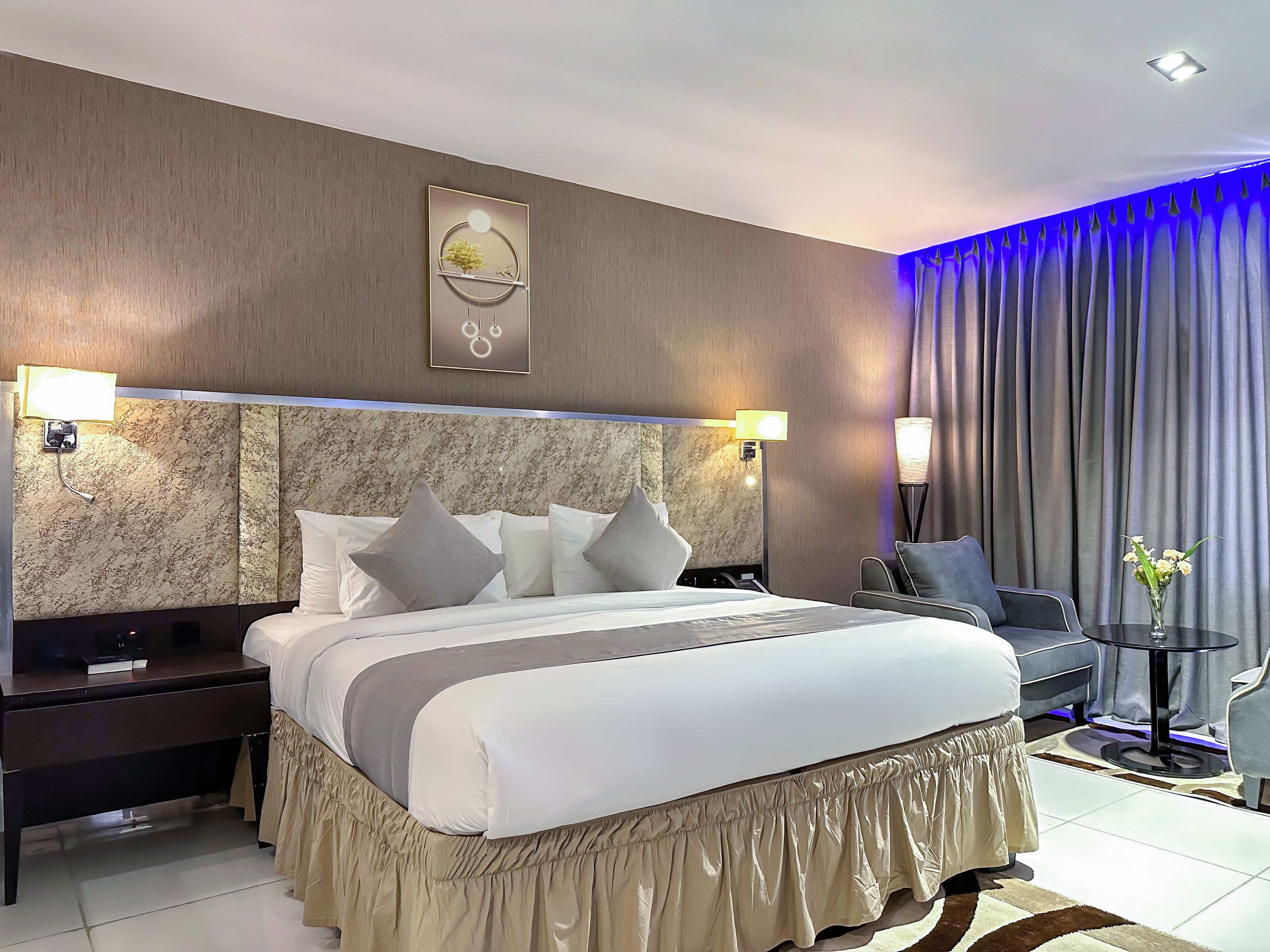 A hotel room with a large bed, a desk, a chair, and a small table.