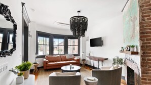Uma sala de estar moderna com sofá, poltronas, mesa de centro, lareira e uma janela grande.