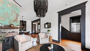 Uma sala de estar ampla, com lareira, área de jantar e escada para outro andar.
