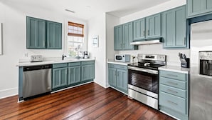 Una cocina moderna con armarios color turquesa, electrodomésticos de acero inoxidable y piso de madera.
