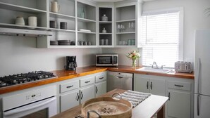 Una cocina moderna con armarios blancos, encimera de madera, estufa, microondas y tostadora.