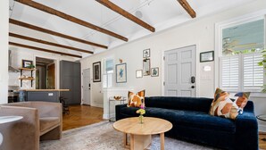 A modern living room with a dark blue sofa, a round wooden coffee table, and a beige armchair.