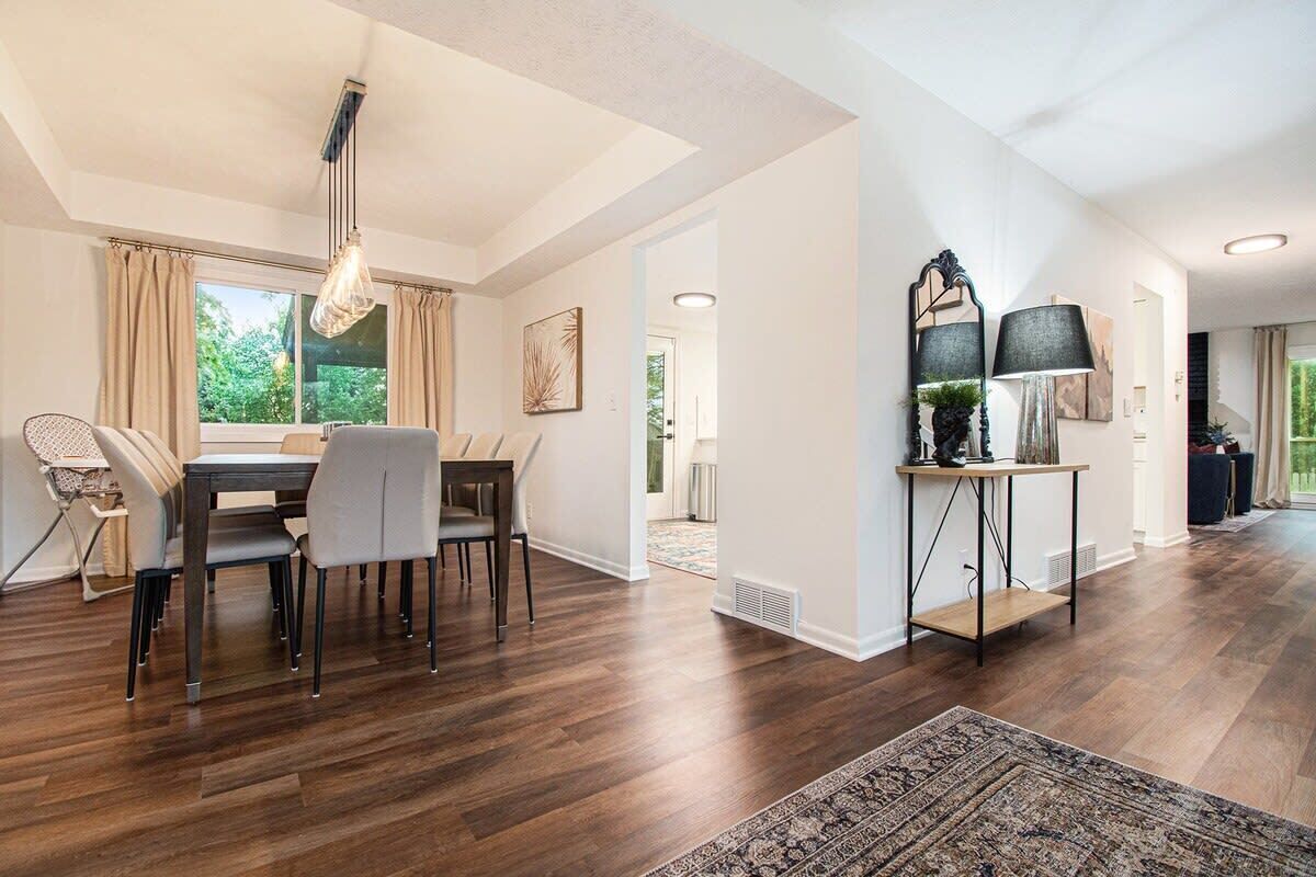 A spacious living room with a dining area, large windows, and a modern chandelier.