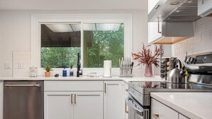 Una cocina moderna con armarios blancos, un lavavajillas de acero inoxidable y un horno empotrado.
